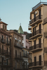 Church dome with cross between old residential buildings in southern Italy