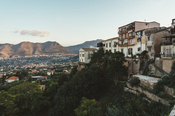 Obraz premium Houses on hillside overlooking valley and mountains at sunset in Sicily