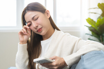 Presbyopia, Hyperopia middle aged asian woman hand rubbing her eye with vision blurred ,girl trying to read text message from smart mobile phone screen, eye disease of old, eyesight farsightedness.