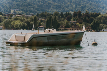 Small motorboat floating peacefully on calm lake water near green coast