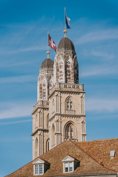 Grossmunster church towers rising above zurich with swiss flags flying high