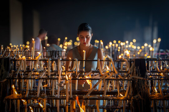 Chica joven creyente rezando y poniendo una vela a la virgen del Rocio en su Santuario