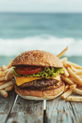 Delicious cheeseburger with fries served on a wooden table near the ocean at sunset