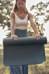Woman folding and unfolding yoga mat in the park during sunset sunrise time.