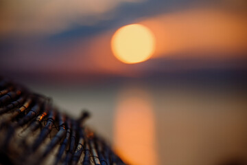 Sky with light clouds over the sea. In the foreground a bamboo sunshade. Sunset