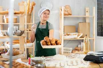 Young woman baker are happy with large amount of made bread products, bakery production, storage...
