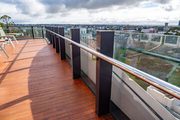 Contemporary rooftop balcony featuring timber flooring, glass balustrades, and expansive city...