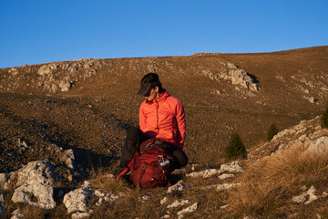 A female hiker unpacks her gear and relaxes after a challenging day of mountain trekking, enjoying...