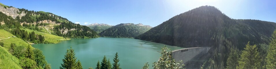Scenic panorama of a serene lake surrounded by lush green mountains