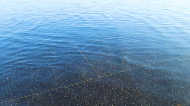 Beautiful, smoothly flowing background of water on marble slabs with reflection of blue sky.