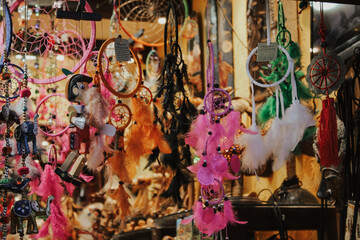A colorful assortment of dreamcatchers with feathers and beads hanging in a market stall, rich in texture and vibrant colors.