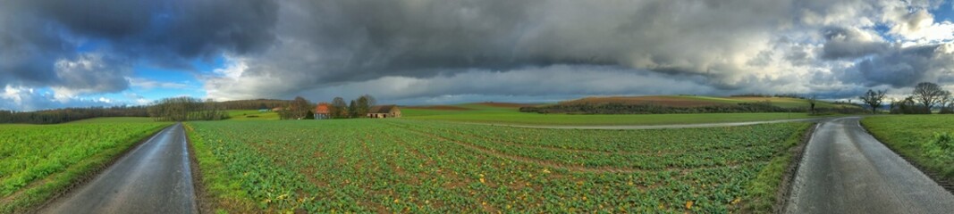 Wide panoramic view of a rural landscape with dramatic stormy clouds overhead