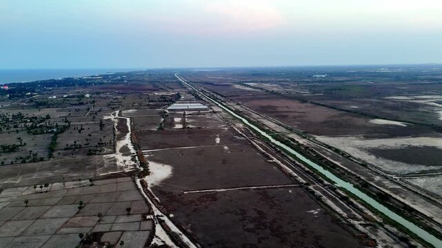 Wide-angle perspective showcasing Chennai's unique blend of rural and coastal beauty. The patterned fields lead to the serene sea, under a soft twilight or early morning sky.
