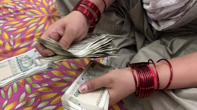 An Indian women counting cash Money, she is sitting on bed