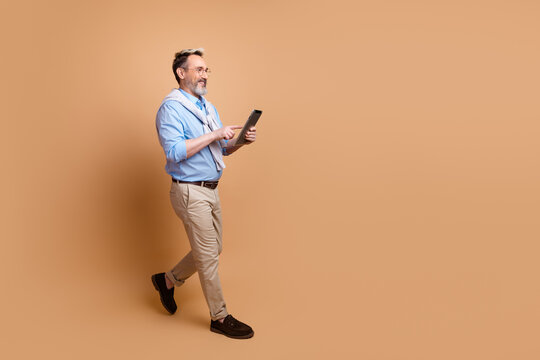 Confident mature man with a tablet on a beige background showcasing professionalism and modern lifestyle values