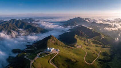 Aerial view of misty mountains with winding roads and a white building