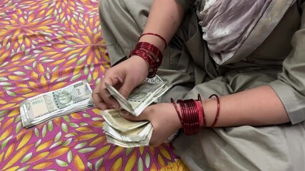 An Indian women counting cash Money, she is sitting on bed - Powered by Adobe
