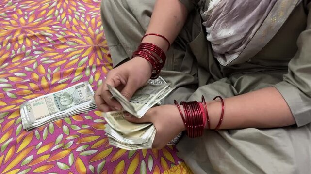 An Indian women counting cash Money, she is sitting on bed