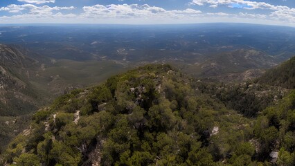 Mountain panorama with a bird's-eye view of the landscape, forest, and clouds