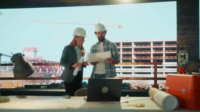 Construction site meeting: engineers discussing blueprints