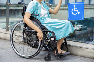 Young disabled woman in wheelchair near handicapped walkway sign, transportation convenience for...