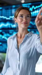 A woman wearing glasses is pointing at a screen with a smile on her face