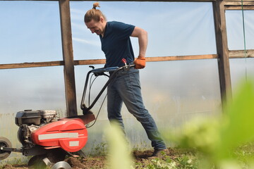 Young man engaged in household chores and small-scale rural farming, tending to his garden with...