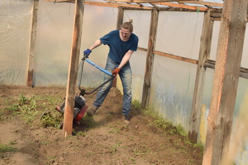 Young man engaged in household chores and small-scale rural farming, tending to his garden with...