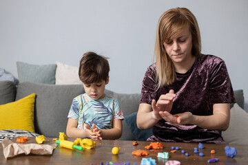 Mother and son creating colorful figures with modeling clay at home
