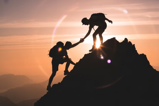 Hikers helping each other reach summit mountain climbing