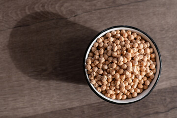 vintage enamel bowl filled with dried chickpeas, the bowl is casting a diagonal shadow across the...