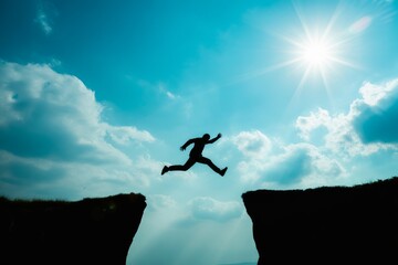 Silhouette man leaping across cliff gap jumping
