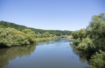 Calm river flowing through lush green forest in Fulda, Germany