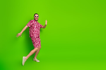 Confident young man in trendy pink leopard print outfit poses against bright green background with...