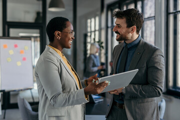 Business colleagues discussing work using tablet in office environment
