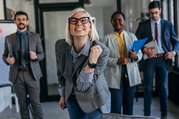 Excited businesswoman celebrating success with team in office