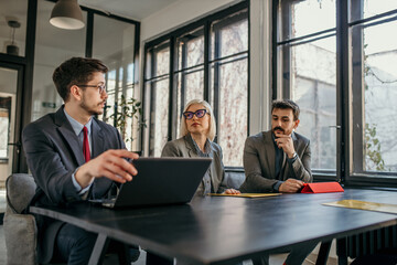 Businesspeople having meeting using laptop in office boardroom