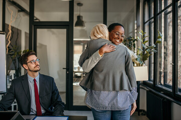 Two businesswomen hugging in office after getting new job