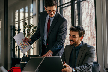 Businessmen discussing growth using charts and laptop in office