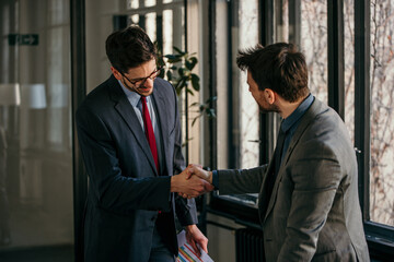 Two businessmen shaking hands after successful meeting in office