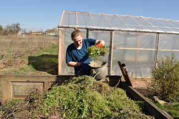 Young man engaged in household chores and small-scale rural farming, tending to his garden with...