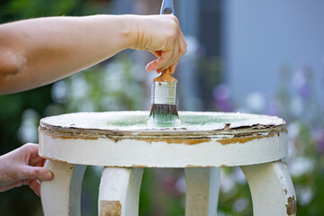 Painting a wooden furniture outdoors, an eco-friendly re-use business.