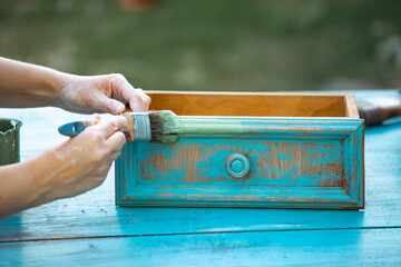 Painting a wooden furniture outdoors, an eco-friendly re-use business.