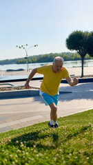 Older man in yellow shirt running uphill in city park. Concept of senior fitness, mobility...