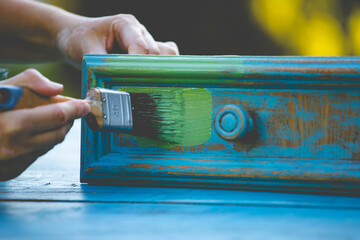 Painting a wooden furniture outdoors, an eco-friendly re-use business.