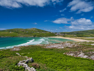 Captivating landscape of Barley Cove Beach, Ireland, with vibrant green hills and a clear blue sky.