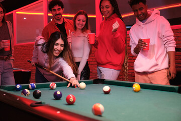 Group of friends enjoying a night out playing pool and drinking in a nightclub