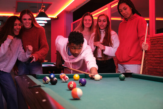 Group of friends playing pool in nightclub, having fun together