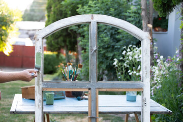 Painting a wooden furniture outdoors, an eco-friendly re-use business.