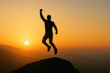 Silhouette of man jumping in victory pose on mountain peak during sunrise symbolizing success motivation and achievement